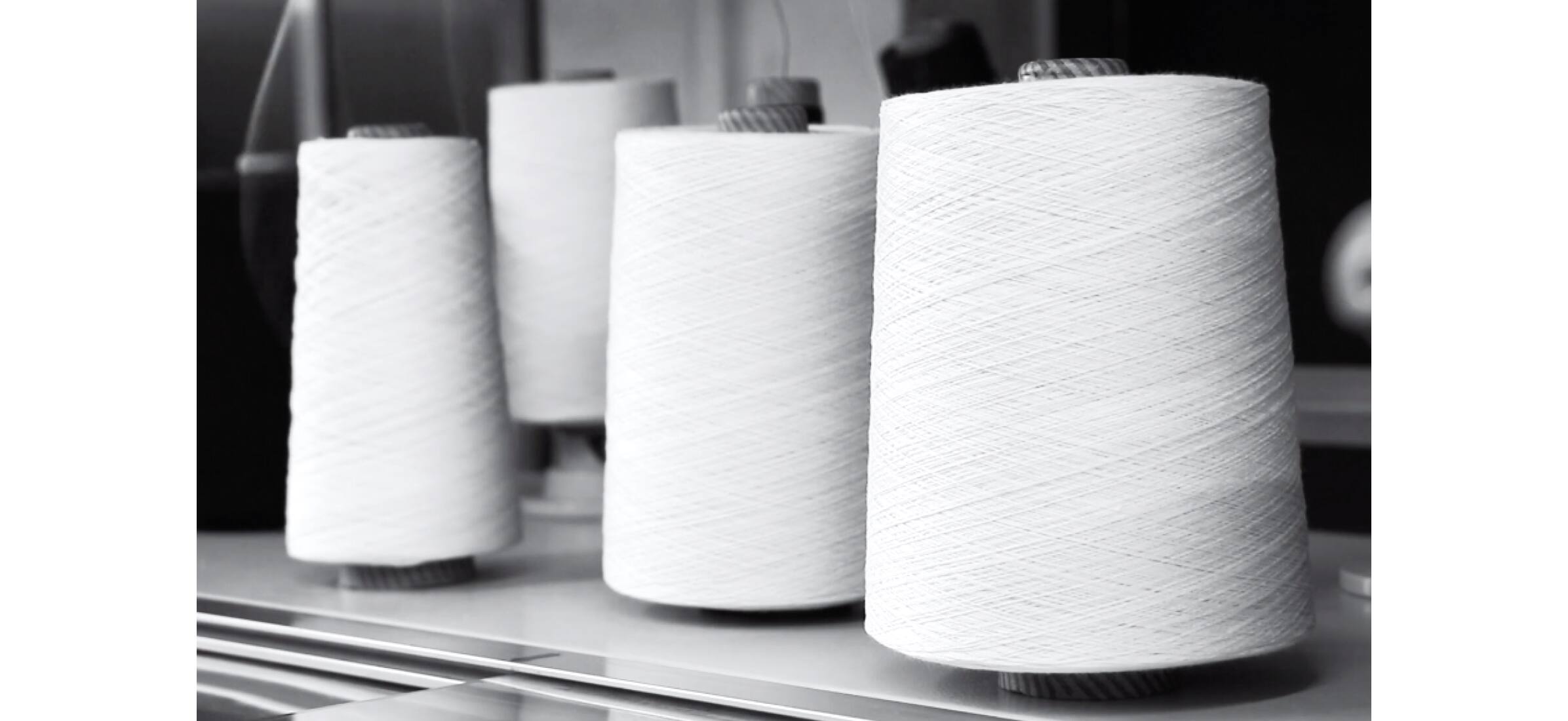 Four spools of white thread sitting on a workshop bench ready for use.